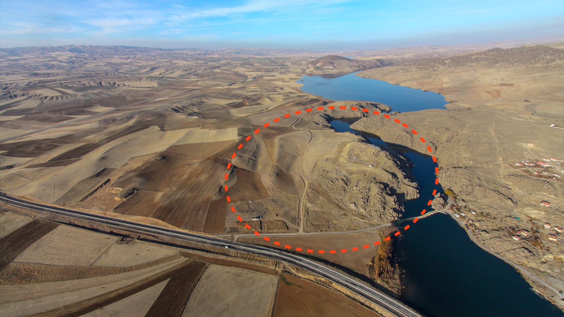 Археологический памятник Бюклюкале в центральной Турции, окруженный сушей, длинным шоссе и большим озером под голубым небом.