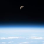 First quarter moon above earth in outer space.