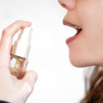 photo of young woman holding up a mouth spray in preparation to spritz it into her mouth