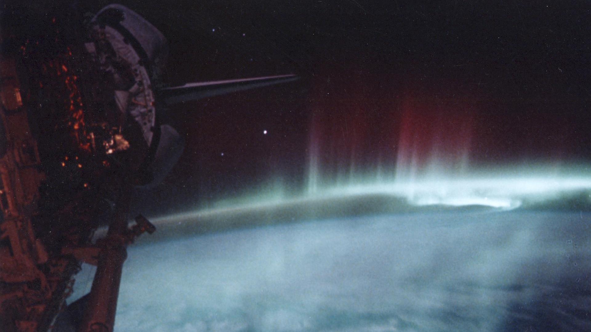 фотография зелено-красного полярного сияния, сделанная во время открытия космического челнока.