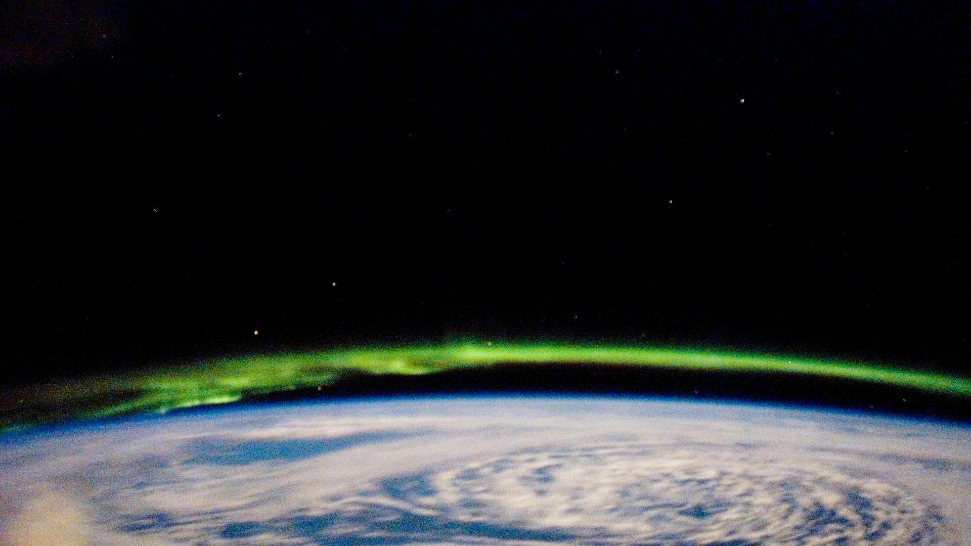 Фотография Северного сияния с зелеными спиральными завитками, сделанная с Международной космической станции.