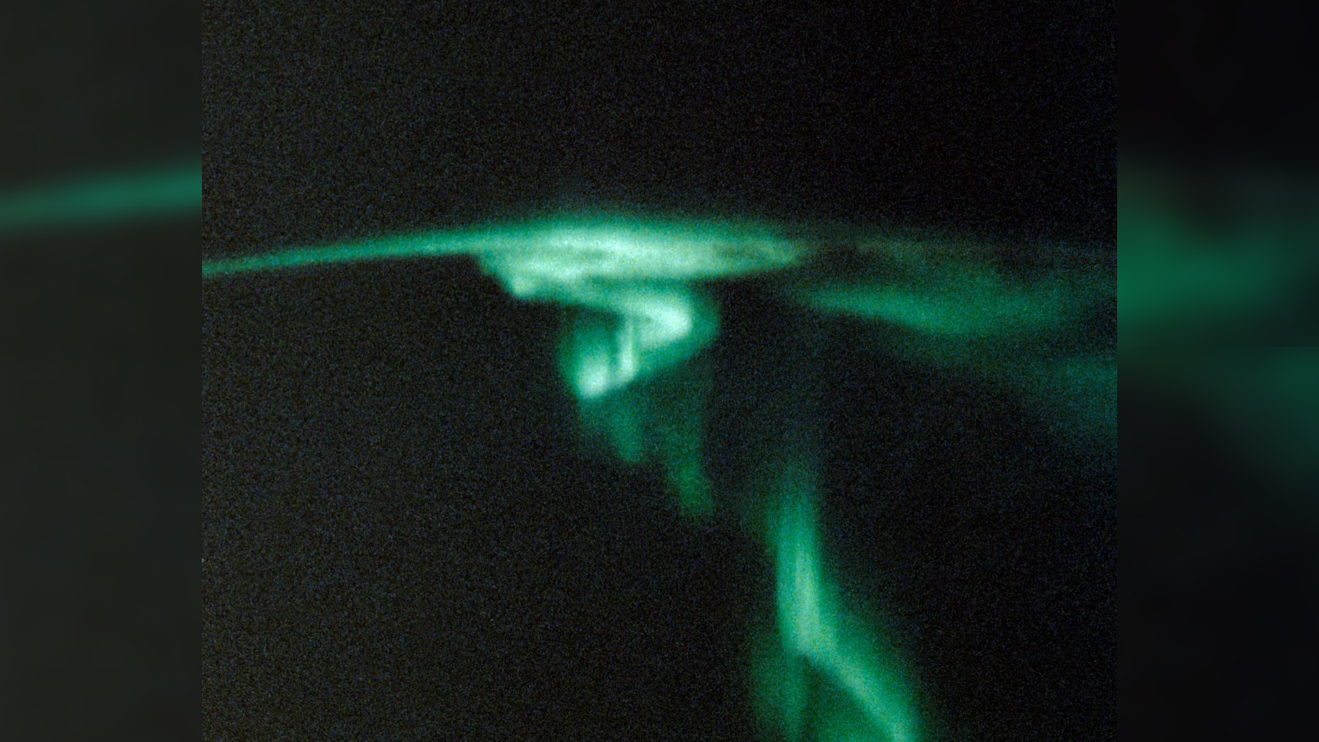 Фотография зеленого полярного сияния спиралевидной формы.