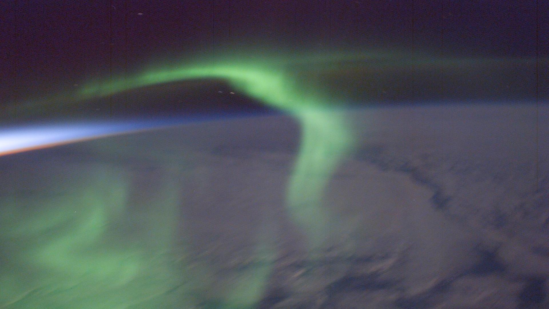 Фотография зеленого полярного сияния над ночной стороной Земли сразу после захода солнца.