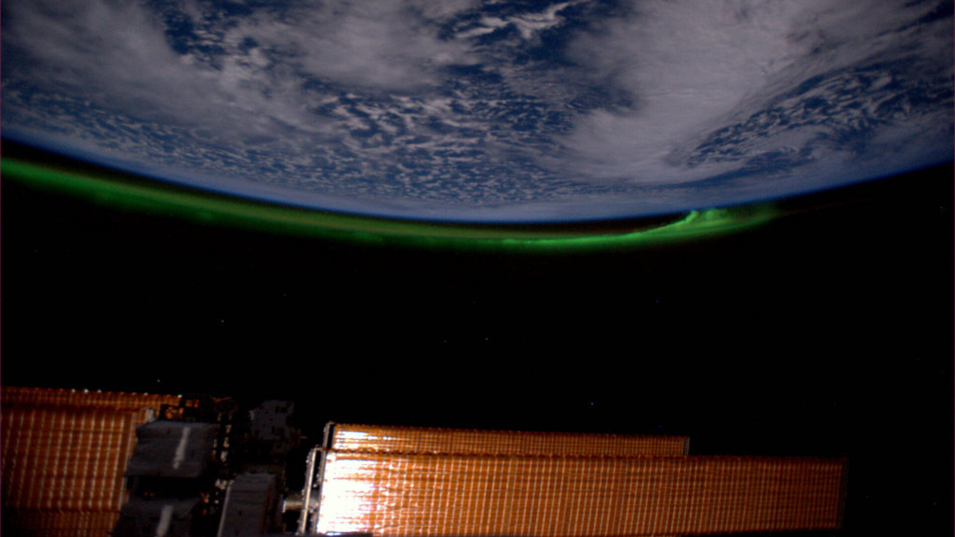 Фотография зеленого полярного сияния, поднимающегося по дуге на перевернутом заземлении.