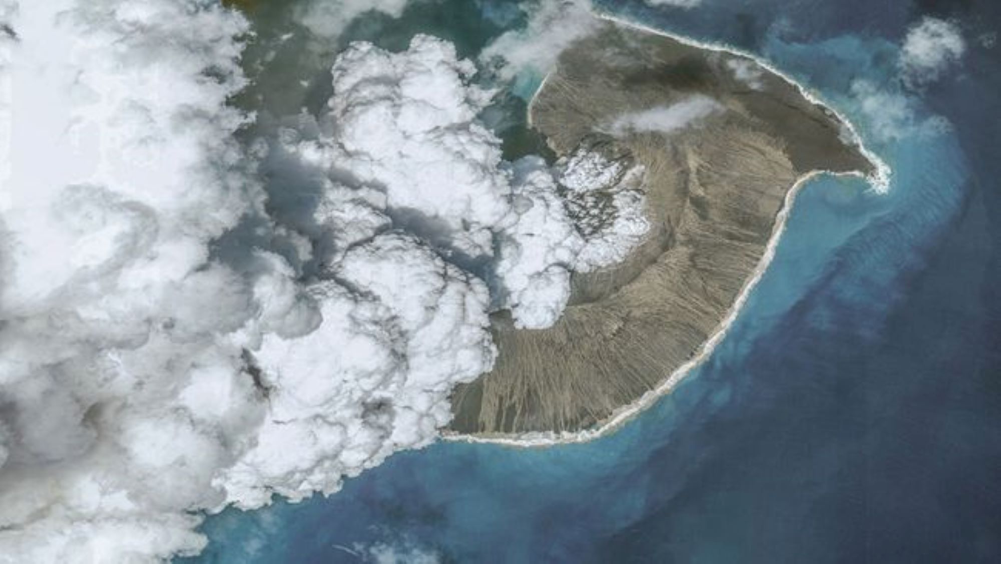 Вид с воздуха на извержение вулкана Тонга в 2022 году. Мы видим пар и пепел, поднимающиеся из вулкана, окруженного водой.
