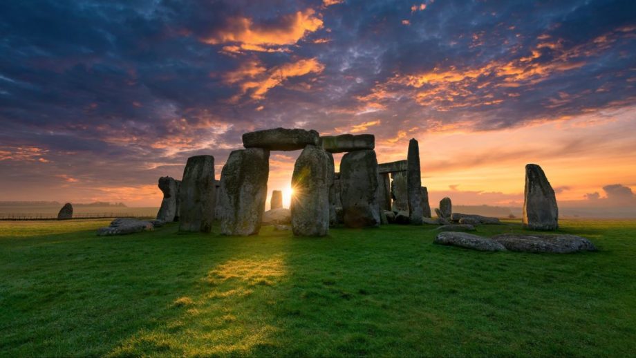 Photo of Stonehenge as the sun is peeking between the stone arches.